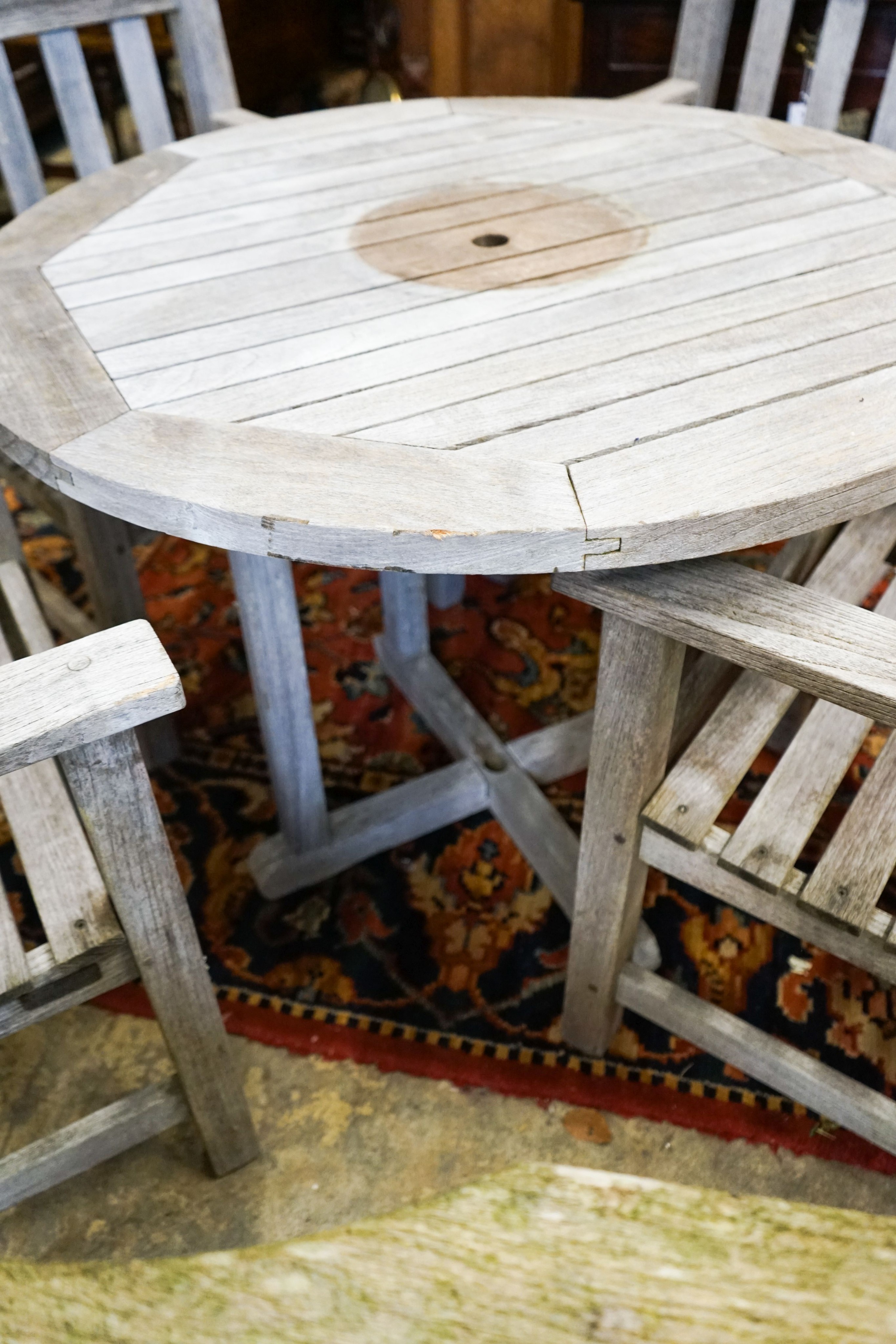 A set of four teak garden chairs and a circular parasol table, diameter 91cm chairs width 60cm